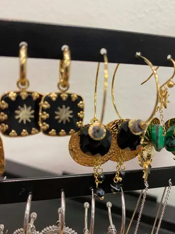 Détail de boucles d’oreilles noires et dorées.