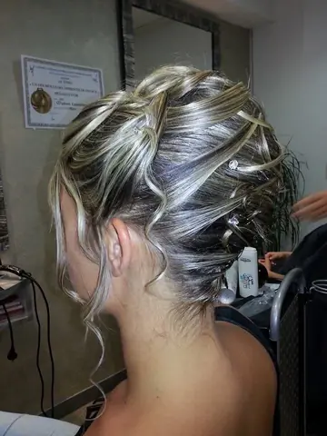 Chignon blond aux mèches entrelacées, ponctué de petits strass.