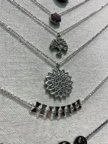 Colliers argentés à pendentifs présentés sur un support en tissu.
