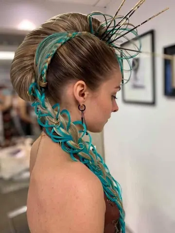 Coiffure artistique avec tresse et mèches turquoise, vue de profil.